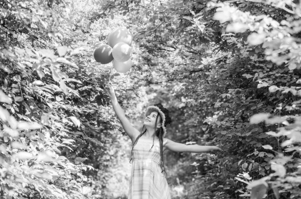 Glad liten flicka i halmhatt med ros blommor i sommar natur med fest ballonger, drömmar — Stockfoto