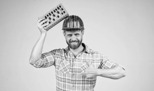 Όμορφος άνθρωπος χτίστης στην κατασκευή κράνος ασφαλείας και καρό πουκάμισο στο εργοτάξιο με τούβλο, τούβλο — Φωτογραφία Αρχείου