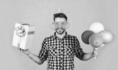 Kareli gömlekli genç adam parti balonları ve hediye kutusu, doğum günü