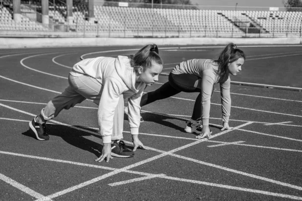 I bambini iniziano a correre in pista. infanzia sana. allenamento all'aria aperta. corridore sicuro. cominciano la loro strada. Pronti a partire. ragazze adolescenti che si scaldano sullo stadio. bambini in abbigliamento sportivo stretching — Foto Stock