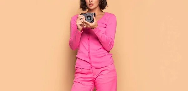Kobieta fotograf ziarna widok trzymając aparat fotograficzny w dłoniach beżowe tło, fotografia — Zdjęcie stockowe