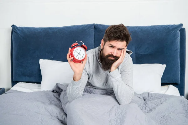 Homem sonolento segurando despertador estar na cama de manhã, hora — Fotografia de Stock