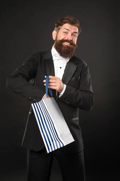 タキシード・ボウのネクタイ姿の幸せな男が買い物袋を背景に黒い服を着ている。誕生日 — ストック写真