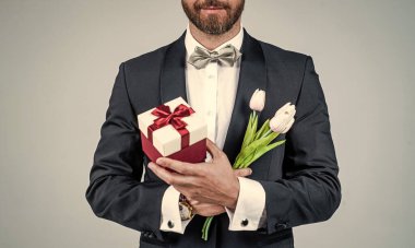 Mutlu kadınlar günü. Zarif adam manzaralı hediye kutusu ve laleleri tutuyor. Bahar çiçekleri. Çiçek dükkanı. Çiçekçiler. Hediyelik eşya dükkanı. 8 Mart, Uluslararası Kadınlar Günü. Tatil kutlaması