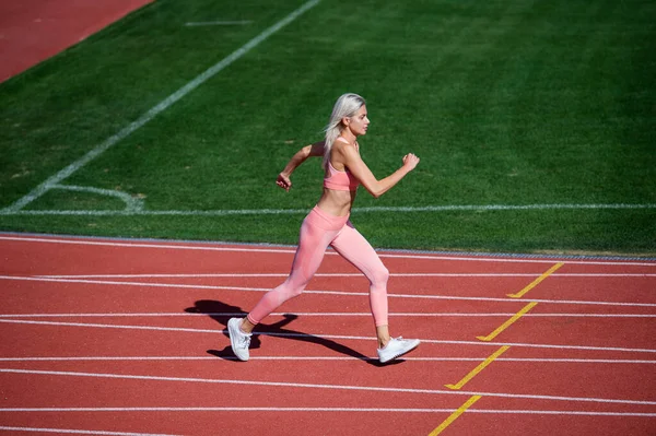 Stora framsteg. kvinnlig idrottstränare i rörelse. hastighet och energi. uthållighet. sexig löpare i motionskläder. sprintning på utomhusarenan travbana. träning och träning. atletisk kvinnlig tränare som springer — Stockfoto