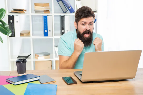 Innoissaan liikemies tekee nyrkit katsomalla kannettavan toimiston työpöytä, ennakointi — kuvapankkivalokuva