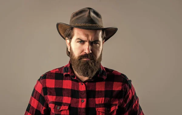 Kovboj s dlouhými vousy. brutální zralý hipster nosí kostkovanou košili a klobouk. divoký západ — Stock fotografie