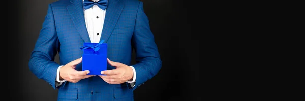 Cropped man in tuxedo bow tie formalwear on black background with box for mens day. copy space — Stock Photo, Image