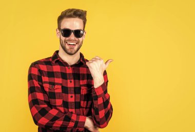 Moda tarzı olan şık bir adam. Kareli gömlek, gözlük ve aksesuar giyiyor.