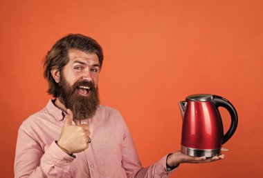 Bu en iyisi. Sakallı hippi ev aletleri kullanır. Mutfak konsepti Bıyıklı vahşi yakışıklı adam çay içiyor. Olgun koca elektrikli su ısıtıcısı tutar. Hayattaki modern teknoloji