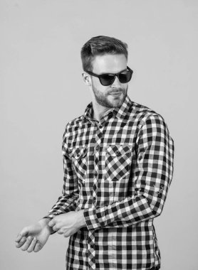 Kareli tişörtlü ve güneş gözlüklü genç yakışıklı adamın yüzünde tüyler var.