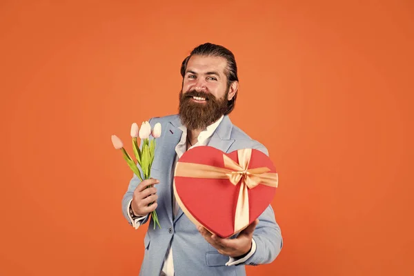 eternal love. spring present. true gentleman with bouquet. love date concept. bearded man in formalwear with tulip flowers and box. elegant businessman wear elegant apparel for formal event