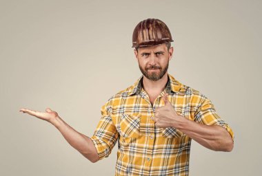 İnşaat kasklı yakışıklı ustabaşı ve inşaat alanında kareli gömlek. Ürün sunumu, fotokopi alanı, en iyi servis.