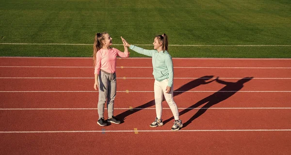 Ik heb een kleine pauze. Veel plezier. Tienermeisjes warmen op in het stadion. Kinderen in sportkleding nemen vijf minuten pauze. kinderen ontspannen na het sporten op racebaan. een gezonde jeugd. workout op frisse buitenlucht — Stockfoto