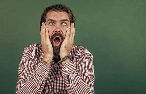 Surprised mature bearded man teacher in school classroom with blackboard, surprise — Stock Photo, Image