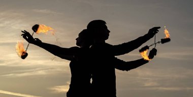 Birbirine aşık çiftler, gece gölgelerinde dönen ateş poi yaparlar açık havada, yanan gökyüzünde.