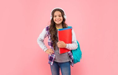 Kulaklıkla müzik dinleyen pozitif çocuk okul çantası, çalışma kitabı, modern hayat..