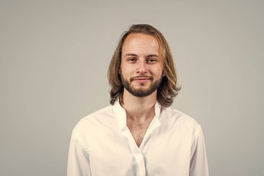 Uzun saçlı, traşsız bir adam. Gülümseyen mutlu adam beyaz ofis gömleği giyiyor. Kendine güvenen ve karizmatik bir iş adamı. Sakallı neşeli menajer. Erkek güzellik ve moda. başarı