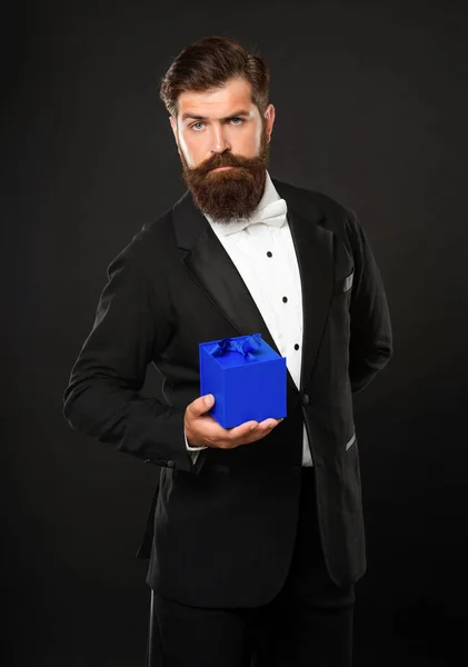 タキシードの弓のネクタイ姿の男が黒の背景に箱をつけて。バレンタインデー — ストック写真