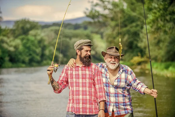 Tempo in famiglia. Attività e hobby. Pesca d'acqua dolce lago stagno fiume. Pescatore con canna da pesca. Uomini barbuti che catturano pesci. Uomo maturo con amico pesca. Vacanze estive. Felice gente allegra — Foto Stock