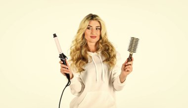 İhtiyaçlarınız için doğru saç maşasını seçin. Saç stili oluşturun. Uzun kıvırcık saçlı kadın saç maşası kullanıyor. Kuaför ipuçları. Sevimli sarışın kız. Çevrimiçi iş. Farklı paketleme teknikleri kullanarak