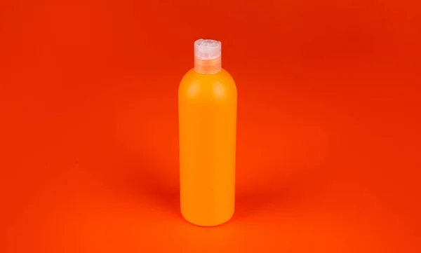 Μπουκάλι σαμπουάν σε πορτοκαλί φόντο, προϊόν ομορφιάς — Φωτογραφία Αρχείου