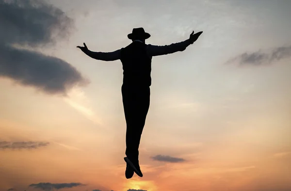 Silhuett av människan flyter i soluppgången himmel med upphöjda händer, frihet — Stockfoto