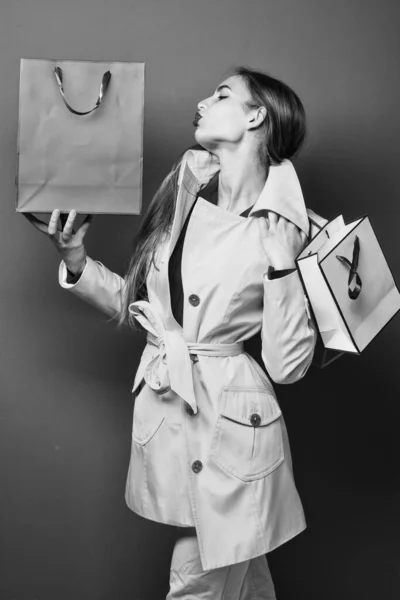 Η γυναίκα απολαμβάνει τα ψώνια. Κουβαλάει τσάντες για ψώνια. Γυναίκα αγοραστής. Χαρούμενη γυναίκα που κρατάει δώρο. πορτρέτο ενός ενθουσιασμένου όμορφο κορίτσι κρατώντας τσάντες ψώνια πάνω από το κόκκινο φόντο. Επιλέγοντας το καλύτερο — Φωτογραφία Αρχείου