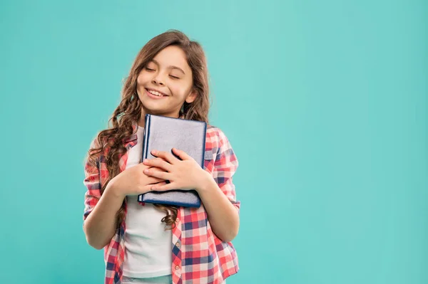 Dromerige tiener meisje holding boek op blauwe achtergrond met kopieerruimte, school — Stockfoto
