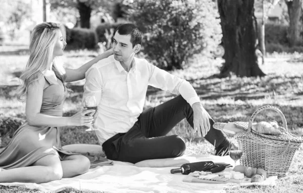愛を通して。緑の草に恋をしてるカップル。自然を共に楽しむ。街の公園でピクニックをしてる。男と女はフードバスケットでリラックス。美しい風景を見てロマンチックな旅行のカップル — ストック写真