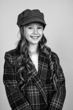 Havalı ve şık. Güzellik ve moda. Neşeli Parisli çocuğun uzun saç stili var. Şık çocuk modaya uygun Fransız şapkası takıyor. Mevsimlik sonbahar modası. Kareli ceketli genç kız. Mutlu çocukluk