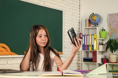 Selfie çekiyordum. Kız üniversite öğrencisi. Okula dönüyorum. Genç kız akıllı telefonlu bir sınıfta çalışıyor. Neşeli çocuk internetten konuyu öğreniyor. Modern eğitim. Bilgi günü. Telefonu olan çocuk öğrenci