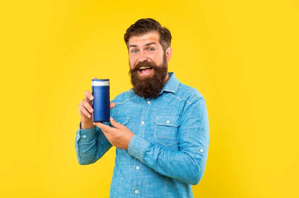 Hombre barbudo brutal asombrado celebrar botella acondicionador de pelo sobre fondo amarillo, cuidado del cabello — Foto de Stock