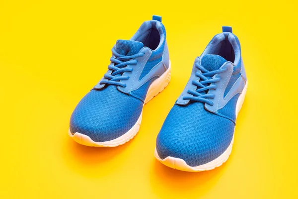 Par de zapatos deportivos azules cómodos sobre fondo amarillo, calzado —  Fotos de Stock