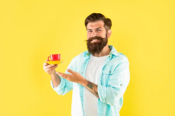 Χαρούμενος αξύριστος άντρας με πουκάμισο που δείχνει καφέ σε κίτρινο φόντο, ποτό — Φωτογραφία Αρχείου
