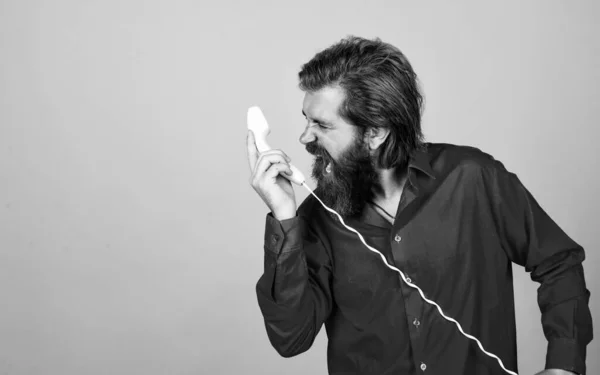 Crier gars occasionnel pendant la conversation. hipster émotionnel aux cheveux longs et moustache. mâle parlant au téléphone rétro. concept de communication. homme barbu en chemise appel au téléphone — Photo