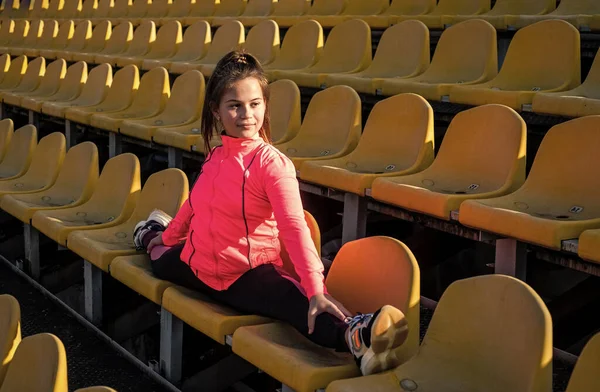 Genç kız açık hava stadı tribününde ikiye bölünmüş olarak oturuyor, jimnastikçi. — Stok fotoğraf