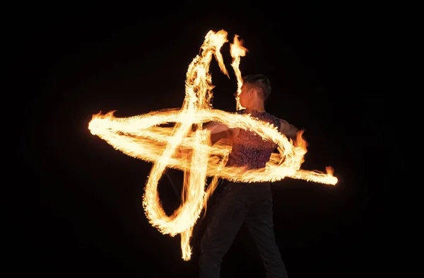 Energetische man performer creëren sprankelende vuurpatronen wervelende brandend stokje in het donker buiten, pyrotechniek — Stockfoto