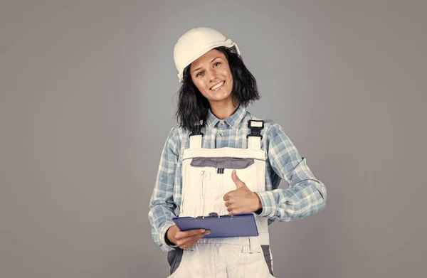 Feliz mujer constructora en la carpeta de documentos de uso de casco protector, construcción —  Fotos de Stock