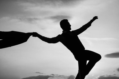 Güneşin doğuşunda özgürce dans eden bir adamın silüeti.