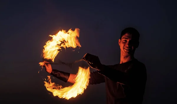 Spel van licht en donker. Vuurspinner 's nachts. Gelukkige mannelijke spinner spin brandende poi. Vuurprestaties. Poi draait en stroomt kunst. Goedenavond. Buitenfestival. Feestdagen vieren — Stockfoto