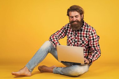 Neşeli hippi bilgisayar kullanıyor. iş dünyasındaki modern teknoloji. Çevik iş. Dijital yaşam tarzı kavramı. Bilgisayarda çalışan olgun bir öğrenci. Adam defter üzerinde çalışıyor. çevrimiçi alışveriş