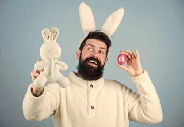 Хіпстер милий кролик синій фон. Великодній кролик. Мій дорогоцінний. Веселий кролик з бородою і вусами тримає рожеве яйце. Великодній символ концепції. Бородатий чоловік носить вуха кролика. Полювання на яйце. Подивіться, що я знайшов — стокове фото