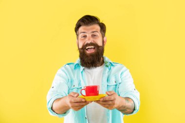 Mutlu beyaz adam gülümsüyor bir fincan sıcak içecek sarı arka plan, çay