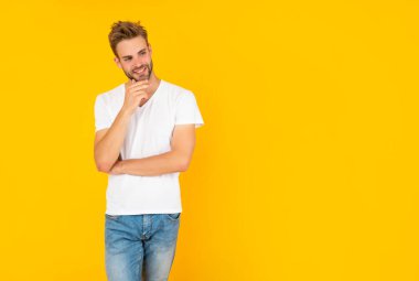 Beyaz gömlekli kıllı adam. Sarı arka planda sakallı genç adam.