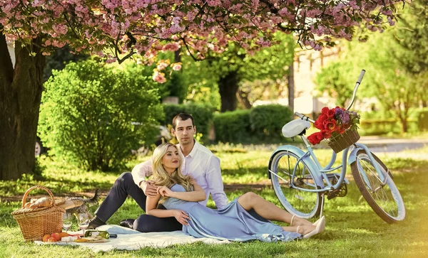 Liefde in blik. ontspannen onder bloeiende sakura. Verliefd stel. We vieren onze trouwdag. gelukkige familie in zomerpark. Eten en drinken. Man en vrouw. Romantisch stel op de picknick. liefdesdatum in het voorjaar — Stockfoto