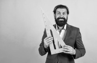Geometri sınavına hazırlanın. Matematik dersi veren bir mimar ya da öğretim üyesi. Okula dönüyorum. resmi eğitim. Ölçü ve boyut. Mutlu olgun öğretmen üçgen tutma aracı. Sakallı adam mühendis cetvel ile çalışıyor.