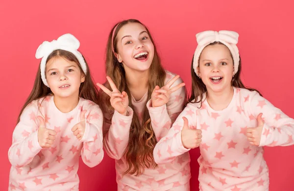 Giving thumbs and v-signs gestures. Happy children in homewear pink background. Kids homewear — Stock Photo, Image