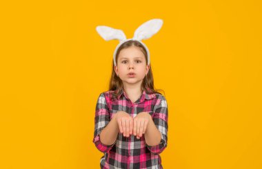Sarı arka planda tavşan kulaklı komik paskalya çocuğu.