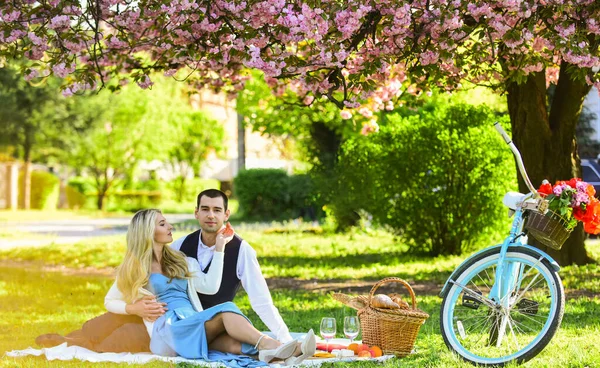 Pareja romántica en el picnic. cita de amor en primavera. relajarse bajo la floreciente sakura. pareja enamorada. celebrando el aniversario. familia feliz en el parque de verano. comida y bebida. hombre y mujer —  Fotos de Stock